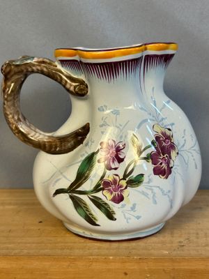 a white vase with purple flowers on it sitting on a table