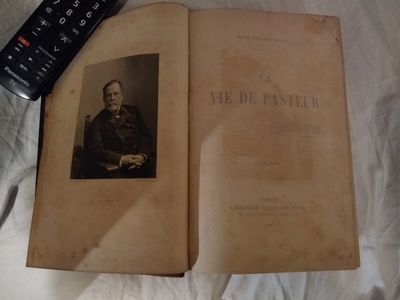 un vieux livre sur lequel figure la photo d'un homme et une télécommande