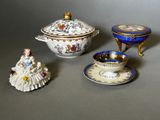 three miniature figurines sitting on a table next to a bowl and saucer