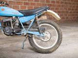 a blue dirt bike parked in front of a brick wall
