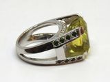 bague en argent sertie d'une pierre jaune entourée de pierres vertes et blanches