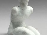 sculpture of a woman sitting on her knees on a gray surface