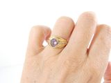 a woman ' s hand holding a ring with a purple stone on it