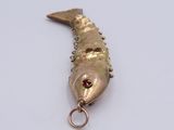 a gold fish charm with a red stone on it