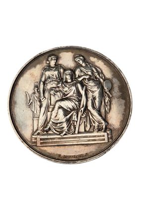 une médaille ancienne en argent représentant une femme et deux hommes sur un piédestal