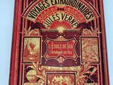 an old book with a red cover sitting on top of a table