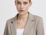 the woman is wearing a tan jacket and black pants