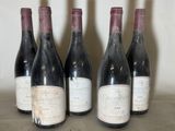six bottles of red wine are lined up on a table