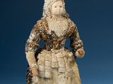 statue of a woman in a dress and bonnet with a basket on her lap