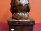 statue en bois représentant un homme assis sur une caisse en bois