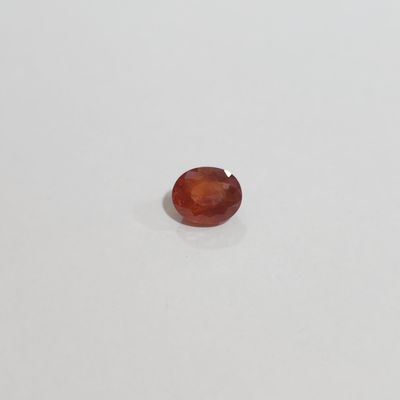 an oval shaped red garnetite stone on a white surface