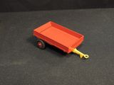 a red toy truck with a yellow handle sitting on a black surface