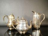 trois théières en argent et une cafetière posées sur une table