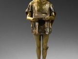 une statue en bronze représentant un garçon tenant un livre