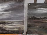 two paintings that are sitting on a easel on a table