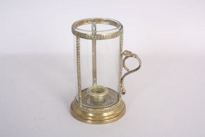 a small glass and brass clock on a white surface