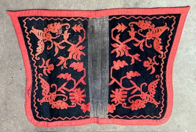 an old black and red piece of cloth with flowers and birds on it