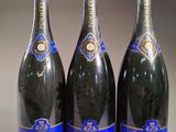 trois bouteilles de champagne sont alignées sur une table