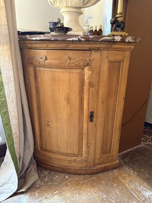 a wooden cabinet in the corner of a room with a vase on top of it
