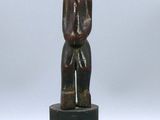 une image représentant une petite statue en bois d'un homme sur un socle