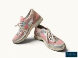 une paire de chaussures roses et blanches à lacets posées sur une surface blanche