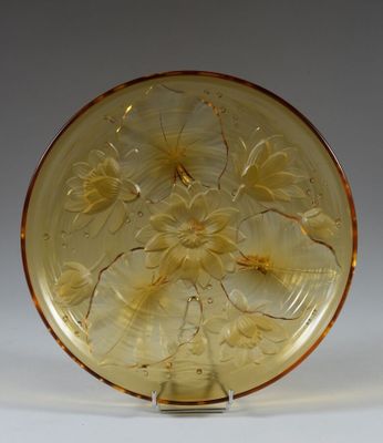 yellow glass plate with flowers and leaves on it on a stand