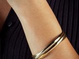 the woman is wearing a gold bracelet and a black shirt