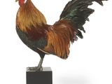 une statue représentant un coq posé sur un socle noir