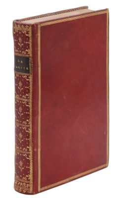 un vieux livre à la couverture rouge et à la bordure dorée