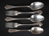 quatre cuillères en argent et une fourchette sur fond noir