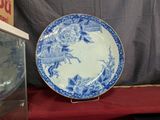 une assiette bleue et blanche posée sur une table à côté d'une horloge