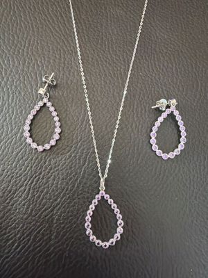 un ensemble composé d'un collier et de boucles d'oreilles ornés de cristaux roses sur un fond en cuir noir