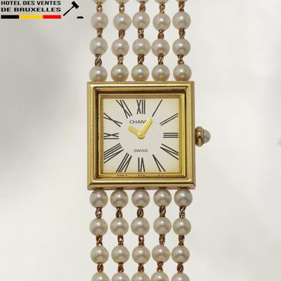 une montre en or avec un cadran blanc orné de perles