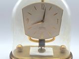 une horloge placée sous un dôme en verre, posée sur une table