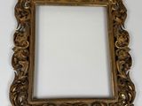 an ornate gold frame with a white background and a white wall