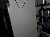 un réfrigérateur blanc dans une pièce où sont rangées des casseroles et des poêles sur des étagères