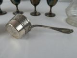 a spoon with a spoon rest sitting on a table next to cups