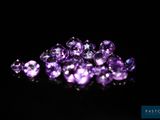 a bunch of purple diamonds sitting on top of a black surface