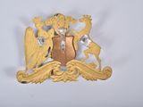 a gold coat of arms with a shield and two birds on it