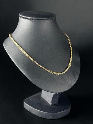 un collier en or posé sur un support de mannequin devant un fond noir