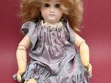a doll that is sitting on the ground with a hat on