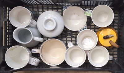 de nombreuses tasses et soucoupes dans un panier posé sur la table