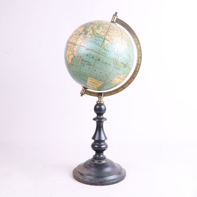 un vieux globe terrestre posé sur un socle, avec un fond blanc