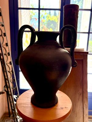 un vase noir posé sur une table en bois devant une fenêtre