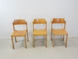 three wooden chairs sitting next to each other in a room