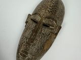 a close up of a wooden mask on a white surface