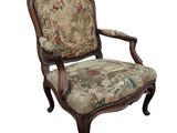 une image d'une chaise en bois dont l'assise est recouverte d'un rembourrage floral