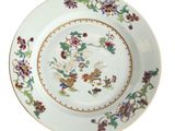 une assiette ornée de fleurs et d'oiseaux sur fond blanc
