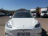the white tesla model s is parked in a parking lot