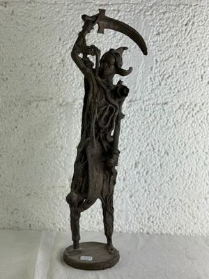 statue d'un homme tenant une faux, posée sur une surface blanche